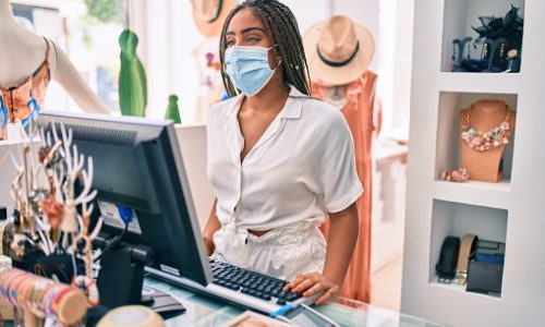 Young african american woman smiling happy working at the till wearing coronavirus safety mask at retail shop